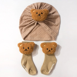 Detail of baby ribbed knit hat and socks set featuring 3D plush bear head decorations