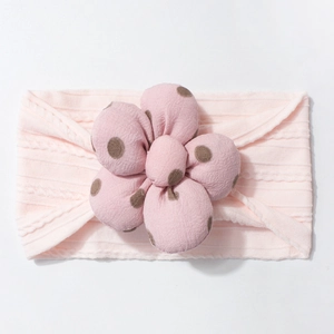 Detail of soft pink ribbed baby headband with large brown polka dot fabric flower accessory