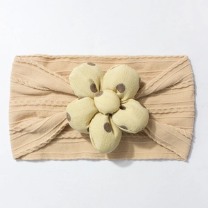 Macro detail of knitted baby headband with a large polka dot 3D flower decoration