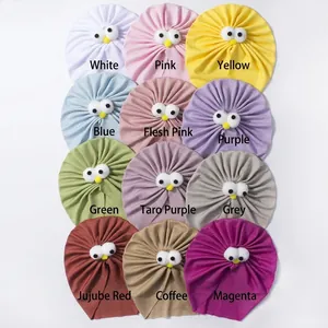 Vue à plat de 12 couleurs de turbans bébé en tricot côtelé doux avec décor yeux mignons