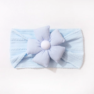 Détail du bandeau bébé bleu tricoté avec une grande fleur en tissu à cinq pétales