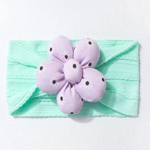 Detail of mint green ribbed headband for babies with a purple floral 3D flower decoration