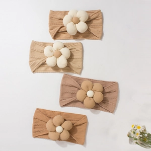 Flat lay of soft ribbed knit baby headbands with handmade floral details in earth tones