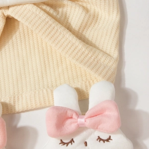 Détail du bonnet tricoté pour bébé avec lapin blanc et petit nœud rose en soie