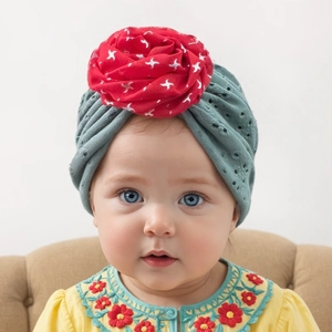 Gros plan d'un turban bébé en tissu ajouré respirant avec une grande fleur rouge décorative