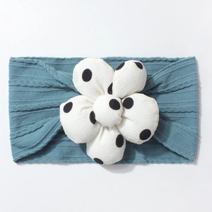 Detail of blue ribbed knit baby headband featuring a large white polka dot floral ornament