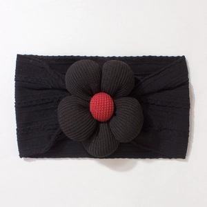 Detailed view of baby headband featuring a large black flower with red plaid button center