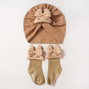 Détail du bonnet turban marron en maille gaufre et chaussettes bébé à décor de lapin