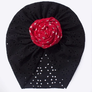 Détail du turban pour bébé en maille ajourée noire avec une grande fleur rouge décorative