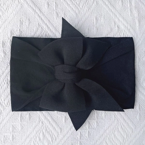 Detail view of a soft black nylon baby headband with a large decorative bow
