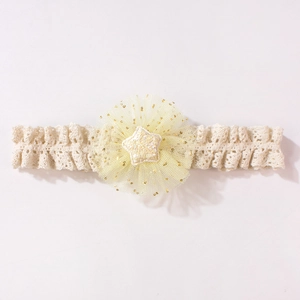 Dettaglio della fascia per neonata in pizzo beige con fiore in tulle giallo e stella dorata