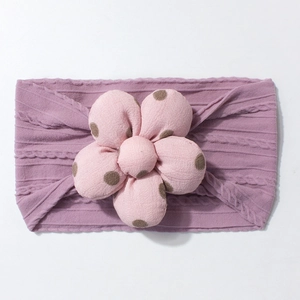 Detail of lavender knit baby headband with pink polka dot flower and cable stitch patterns