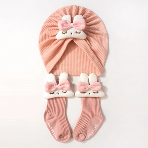 Détail d'un ensemble turban et chaussettes rose pour bébé avec décor lapin peluche