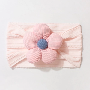 Detailed close-up of pink corduroy flower on elastic knitted baby headband for infants