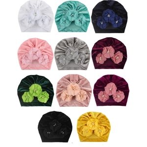 Détail de turbans en velours pour bébé montrant divers coloris et fleurs perlées à la main