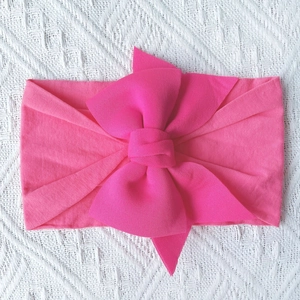 Detailed top view of soft pink nylon baby headband with a large layered bow knot