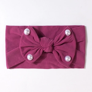 Dettaglio fascia neonata in maglia rosa bacca con fiocco decorato da perle sintetiche