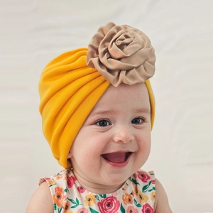Close-up of bright yellow baby turban hat with a large handmade gold satin rose flower