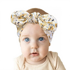 Détail du bandeau bébé blanc avec imprimé floral jaune et grand nœud en oreilles de lapin