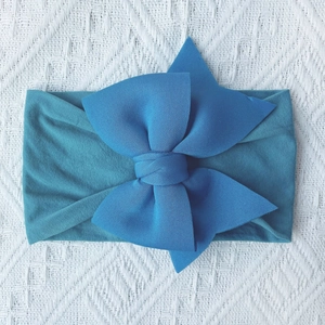 Detailed close-up of navy blue nylon baby headband with a soft double bow on a white blanket