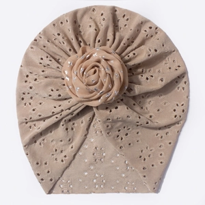 Détail d'un turban bébé tricoté ajouré avec rose en tissu à paillettes et motif respirant
