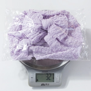 Macro detail of lavender baby headband with textured bow showing 32.1g weight on scale