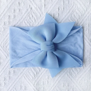 Detail of soft light blue nylon baby headband featuring a large knitted bow for infants