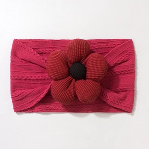 Close-up of deep magenta knitted baby headband with a large ribbed flower and button