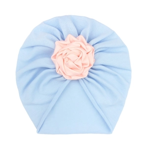 Detail of baby turban hat in light blue knit fabric with a pink satin flower decoration