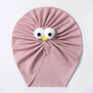 Détail de bonnet turban rose pour bébé avec de grands yeux drôles et pompons