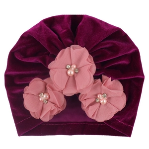 Détail du bonnet bébé en velours violet avec fleurs en mousseline et perles