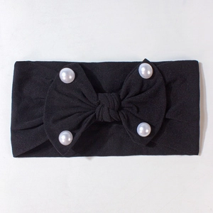 Dettaglio della fascia nera per neonati con grande fiocco e quattro perle bianche decorative
