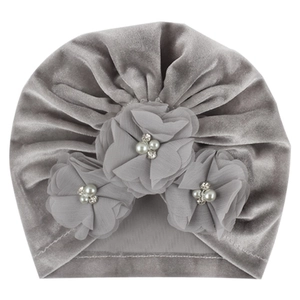 Vue détaillée du turban pour bébé en velours gris foncé avec fleurs en mousseline et perles