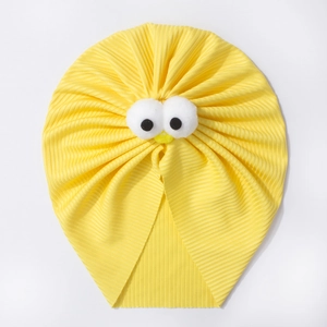 Détail de la texture côtelée jaune et des yeux en peluche sur un bonnet pour bébé