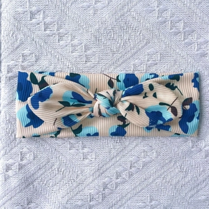 Détail du bandeau bébé en tissu côtelé avec imprimé floral bleu et nœud décoratif