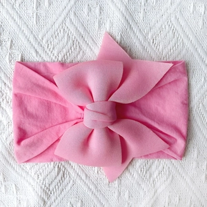 Close-up of soft pink nylon baby headband with a large decorative layered bow detail