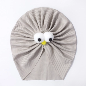 Détail du bonnet turban pour bébé montrant la maille côtelée et les yeux en peluche