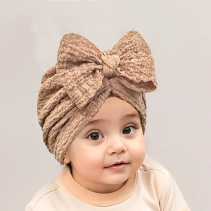 Detail of soft waffle fabric texture and large bow on a beige baby turban hat