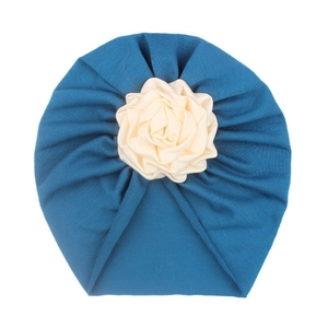 Detail of teal baby turban hat featuring a cream 3D fabric flower and soft pleated fabric