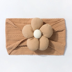 Detailed texture of baby knitted headband featuring a large 3D floral pattern in camel brown