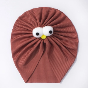 Texture détaillée du bonnet turban pour bébé en tricot rouille avec décor d'yeux de dessin animé