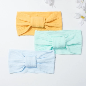 Three-pack of soft ribbed nylon baby headbands with large bows in bright yellow, green, and blue