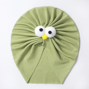 Détail d'un turban bébé en tricot côtelé vert herbe avec d'adorables yeux de dessin animé