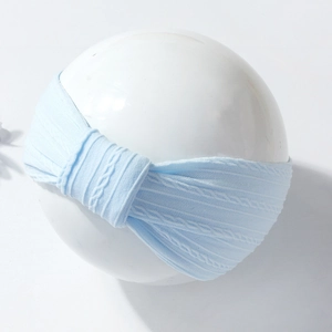 Close-up of light blue ribbed knit baby headband with decorative knotted bow detail