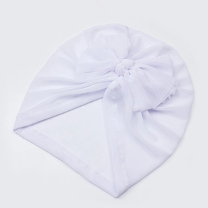 Detailed close-up of white mesh baby turban hat with a large bow on plain white background