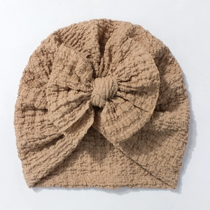 Detail of baby turban hat featuring seersucker texture and a large bow in khaki