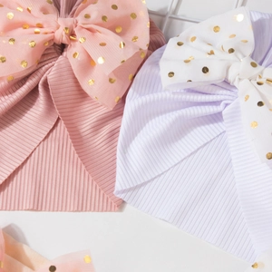 Detail of baby headbands with large mesh bows and gold foil polka dots on ribbed fabric