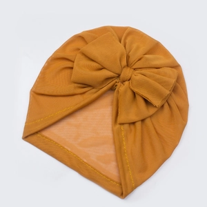 Close-up of mustard yellow mesh baby turban featuring a large bow and delicate stitching