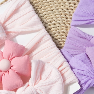 Gros plan de bandeaux pour bébés en tricot avec détails de fleurs 3D rose et violet