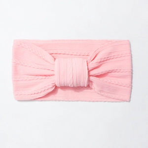 Close-up of pink cable knit baby headband with a central knot on white background